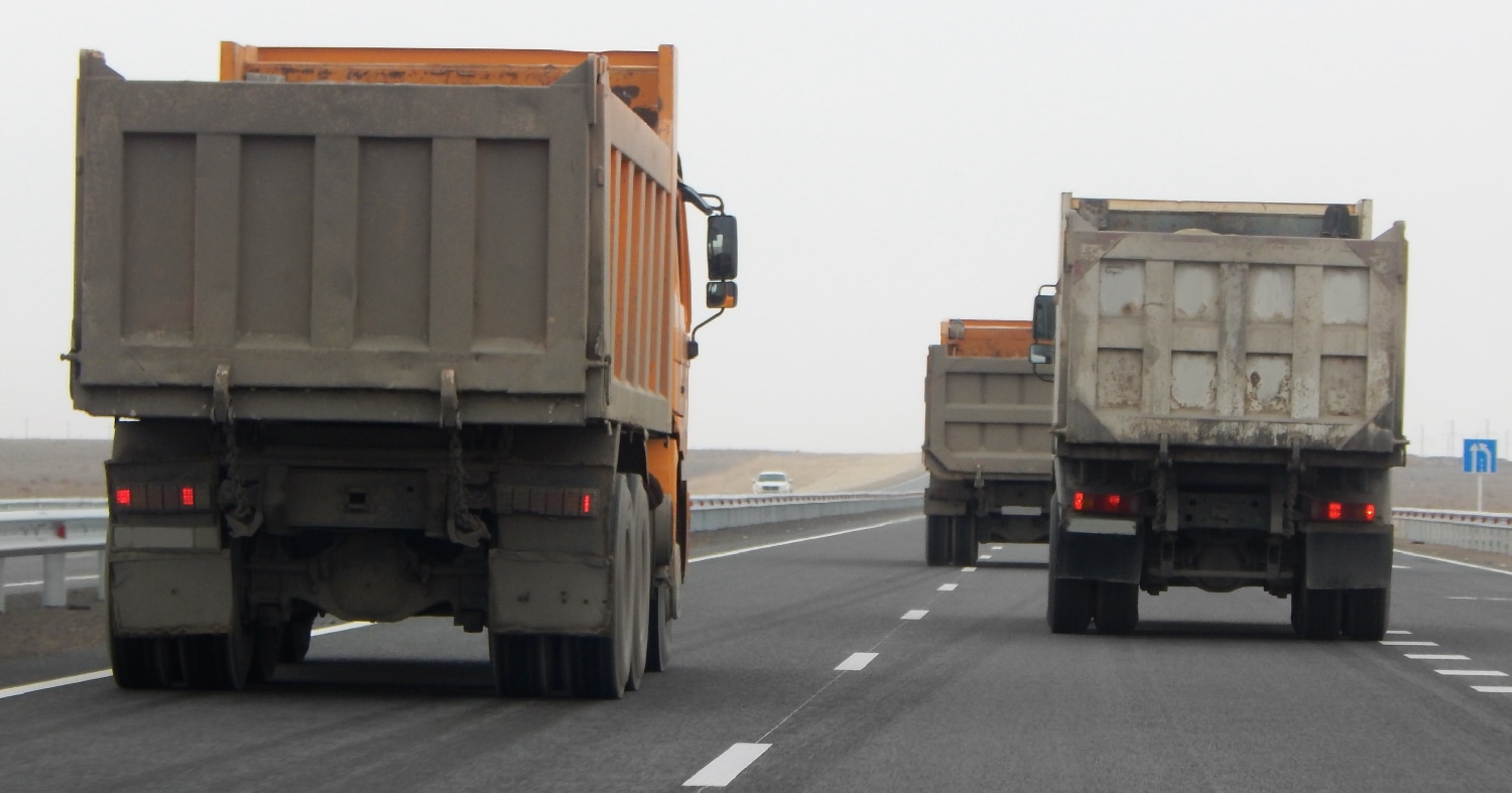 3 dump trucks driving down a 2 lane highway.