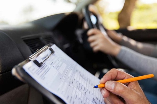 A driver is shown in the background of a person with a clipboard and pen.