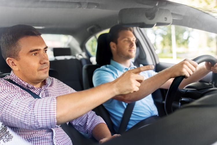 one man in the passenger seat of a car is giving directions to another man in the driver's seat.