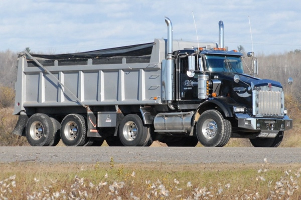 black dump truck driving down a road.