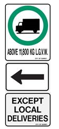A vertical stack of three road signs: the top shows a black truck silhouette inside a green circle with the text "ABOVE 11,800 KG L.G.V.W.", the middle features a black arrow pointing left, and the bottom reads "EXCEPT LOCAL DELIVERIES."