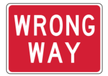 A rectangular red sign with white text that reads WRONG WAY.