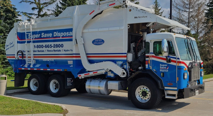 A white and blue Super Save Disposal front-load garbage truck parked in a paved lot, representing career opportunities for Class 3 commercial drivers.
