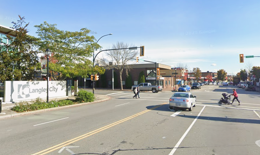 A multilane road with a white car waiting to turn left at a red light.