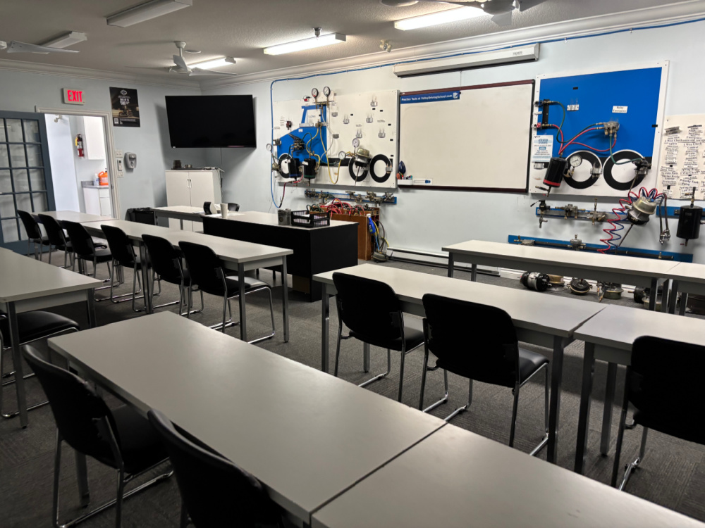 A classroom with tables and chairs, with a working air brake board at the front of the room