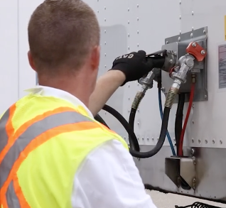 Close-up of a commercial driver connecting emergency and service air lines to a trailer as part of a comprehensive safety and maintenance check.