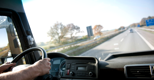 a driver holding the steering wheel while looking out the windshield to see the road ahead.