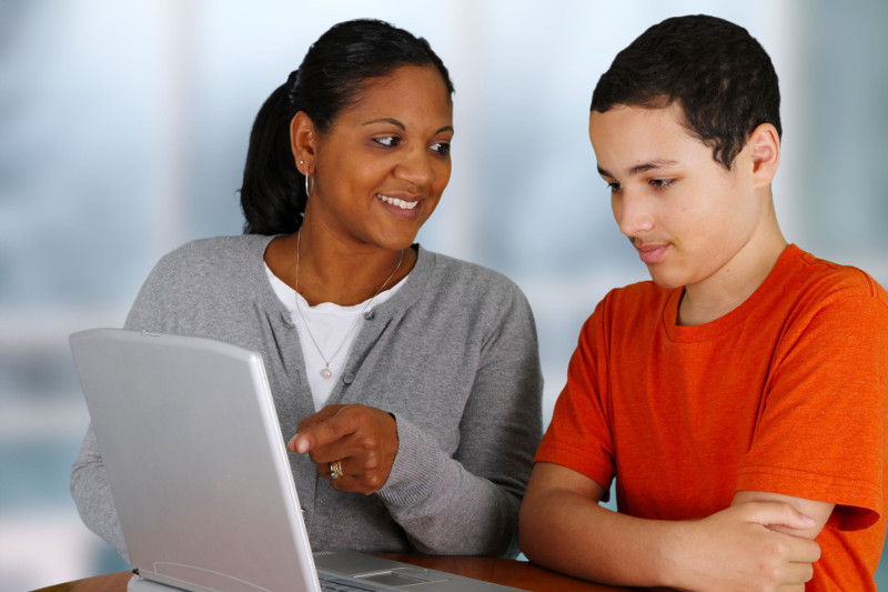 A female instructor helping a young student study on a laptop, preparing for the ICBC knowledge test or an online driver education course.