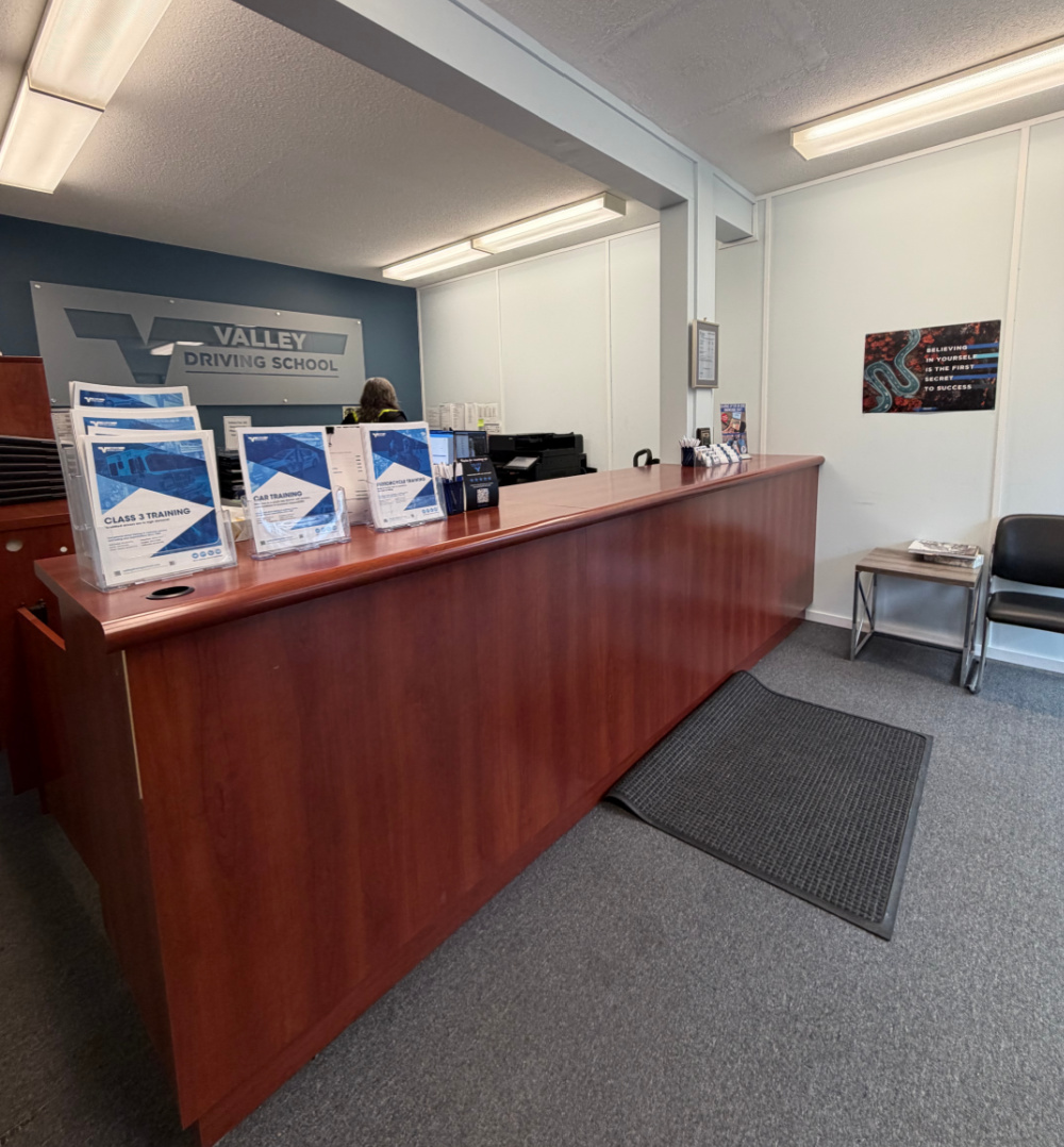 A mahogany reception desk at Valley Driving School with flyers on the counter.