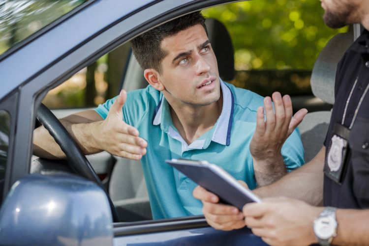A police officer handing a ticket to a driver seated inside a vehicle.